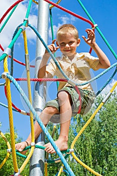 The boy climbs the ropes