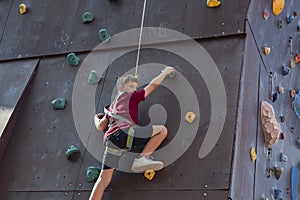 A boy climbs the top of a climbing wall in a sports park climbing wall