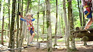 Boy climbs up the agility bridge to a wooden platform on a tree