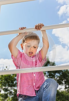 Boy climbs up on a ladder, a bottom view, in the open air against the blue of the sky