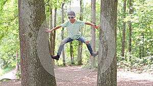 The boy climbs up the trees, jumps to the ground