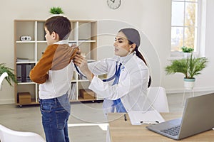 Boy in clinic for a checkup. Doctor with stethoscope examining child& x27;s lungs and heartbeat.