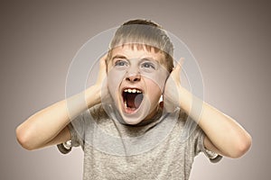 Boy closed his ears with his hands and shouts furiously. Naughty schoolboy. Fear