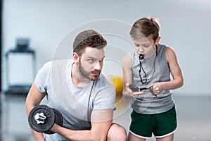 Boy coach training man exercising with dumbbell