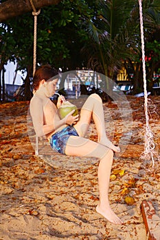 Boy with coconut on the beach swing