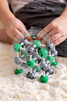 The boy collects from the constructor a model of the molecule of sodium chloride, salt according to the formula. Layout