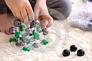 The boy collects from the constructor a model of the molecule of sodium chloride, salt according to the formula. Layout
