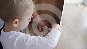 The boy collects a packing cardboard box with his hands, his mother helps him