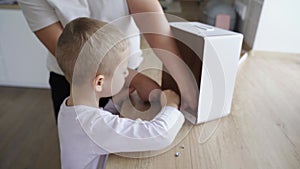 The boy collects a packing cardboard box with his hands, his mother helps him