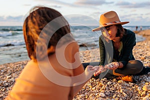 boy collects shells and pebbles in the sea on a sandy beach with his mother. Family having fun on the beach collecting shells