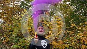 Boy with colored smoke in costume with painted skeleton during Halloween