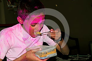 Boy with colorful face eating breakfast. Concept for Indian festival Holi