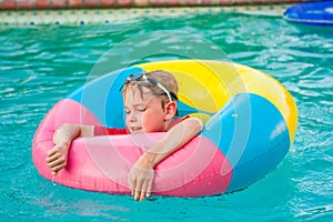 Boy in colorful float ring in swimming pool