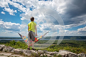 A boy with a colorful kite in his hands against the blue sky with clouds. A child in a yellow T-shirt and shorts. Beautiful