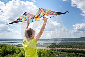 A boy with a colorful kite in his hands against the blue sky with clouds. A child in a yellow T-shirt and shorts. Beautiful