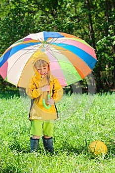 Boy with colorful umbrella playing with ball on