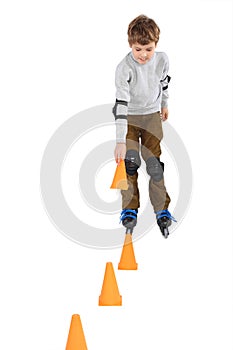 Boy with cone in hand rollerblading near cones