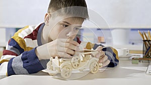 A boy constructs a car from a wooden 3d puzzle.