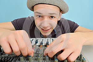 The boy controls the equalizer on the mixing console in the music studio
