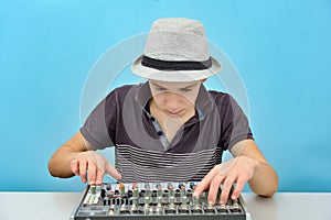 A boy controls a mixing console in a music studio