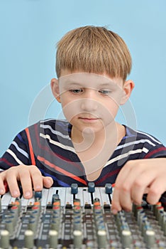 A boy controls a mixing console in a music studio