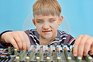 A boy controls a mixing console in a music studio