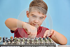 A boy controls a mixing console in a music studio
