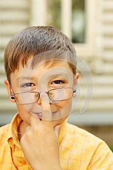 Boy corrects glasses near house