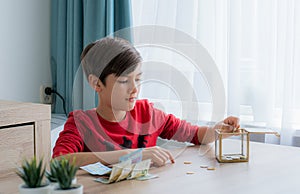 A boy counting money to put in saving box, saving money concept
