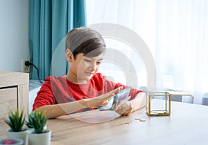 A boy counting money to put in saving box, saving money concept