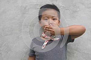 Boy covering his mouth - Asian boy covering his mouth with his hand, doesn photo