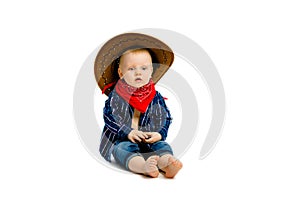 Boy in a cowboy hat sitting on a white floor
