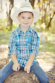 Boy with Cowboy Hat on Tree Trunk