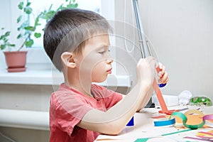 Boy crafting with paper sitting on table, early brain developing