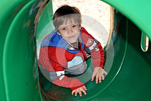 Boy crawling through a playground tunnel