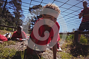 Boy crawling under the net during obstacle course training