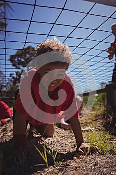 Boy crawling under the net during obstacle course training