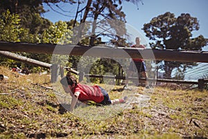 Boy crawling under the net during obstacle course training