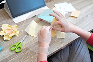 Boy creating paper flower for mom. Mother day, DIY on quarantine or online education concept. Soft focus