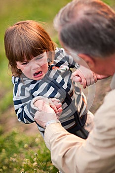 Boy crying hard, eyes shot full of tears, holding hands of grand