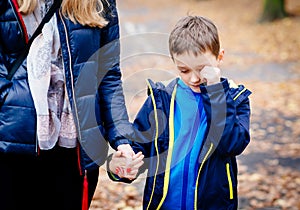 Boy crying and holding his mother hand during the walk