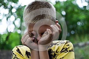 Boy is crying outdoors. The teenager child is crying. Strong resentment of the child.