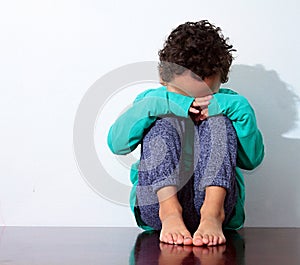 Boy crying in poverty with hand over face stock photo