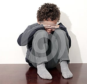 Boy crying in poverty with hand over face stock photo