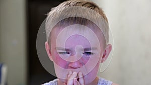 Boy crying. Red face. Child rubs eyes with hands. Close-up