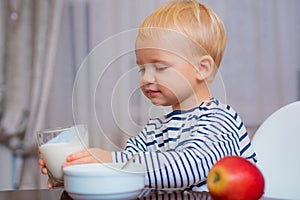 Boy cute baby eating breakfast. Baby nutrition. Eat healthy. Toddler having snack. Drink milk. Child hold glass of milk