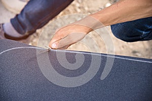 Boy cuts the griptape on a skateboard