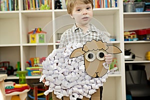 The boy cuts a paper sheep. Early education, fine motor skills.