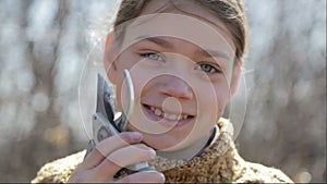 The boy cuts the trees in the garden with a pruner. The child helps to trim the trees in the park in the spring.