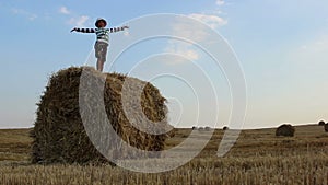 Boy dancing on a haystack in a field